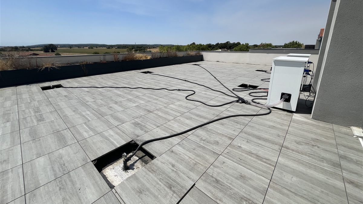 Flexibles d'assèchement raccordés à de discrètes ouvertures dans le dallage d'une toiture-terrasse.